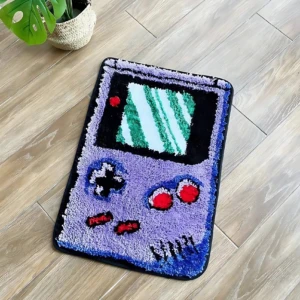 Alfombra de diseño retro estilo Game Boy, con pantalla verde y botones rojos, sobre piso de madera.