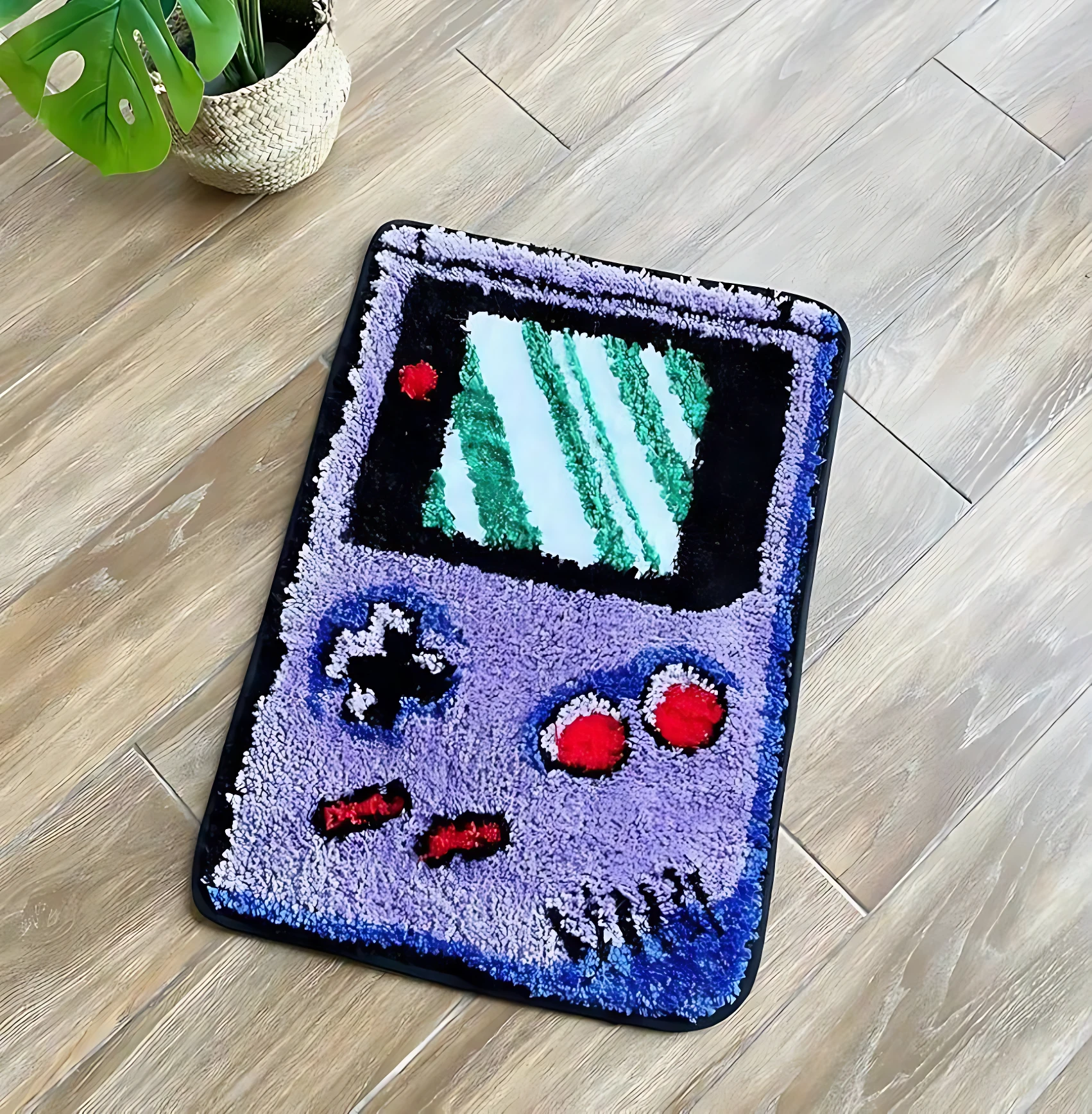 Alfombra de diseño retro estilo Game Boy, con pantalla verde y botones rojos, sobre piso de madera.