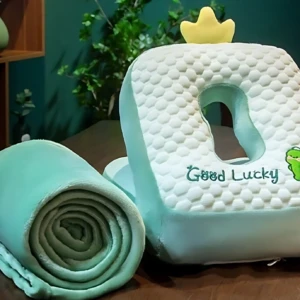 Almohada cobijera en forma de animal con corona amarilla, textura de seda de hielo en color menta, incluye manta enrollada a un lado.