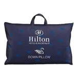 Almohada Hilton Down en funda azul oscuro con logotipo de la marca y símbolo de cisne, presentada en empaque rectangular con asa superior.