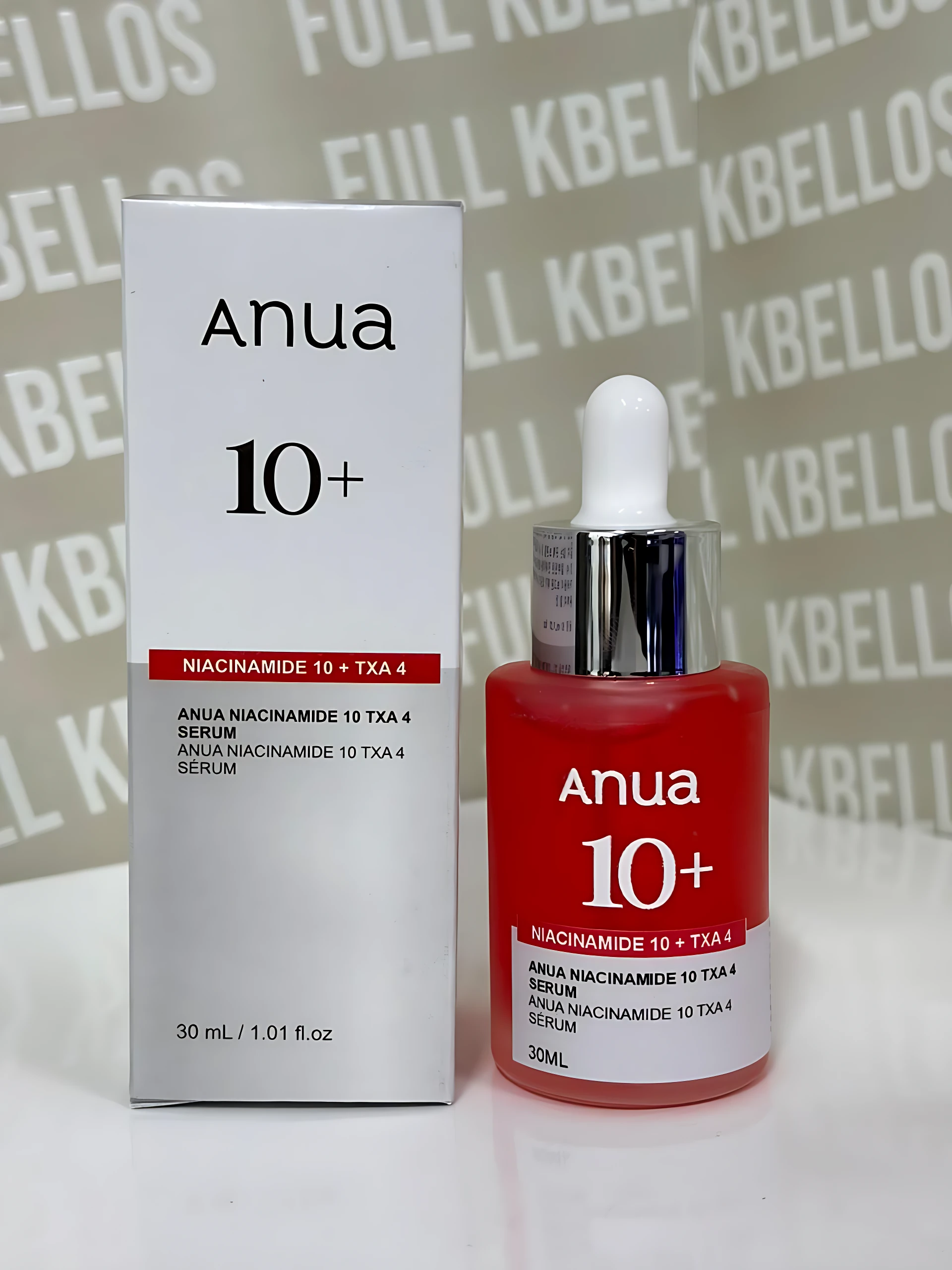 Serum Anua Niacinamide 10 Txa 4 de 30 ml, con envase rojo y gotero, junto a su caja blanca, sobre fondo con patrón repetitivo.