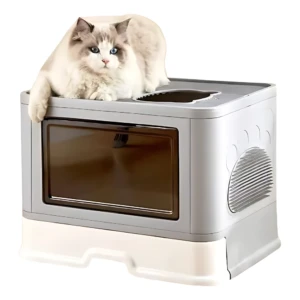 Arenero cerrado para gato en color gris claro con ventana oscura y ventilación lateral, con gato de pelaje blanco y azul recostado sobre la tapa.
