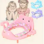 Asiento reductor de baño en forma de elefante rosa con patas y orejas, diseño animado para niños, incluye variante azul y morada en esquina superior derecha.