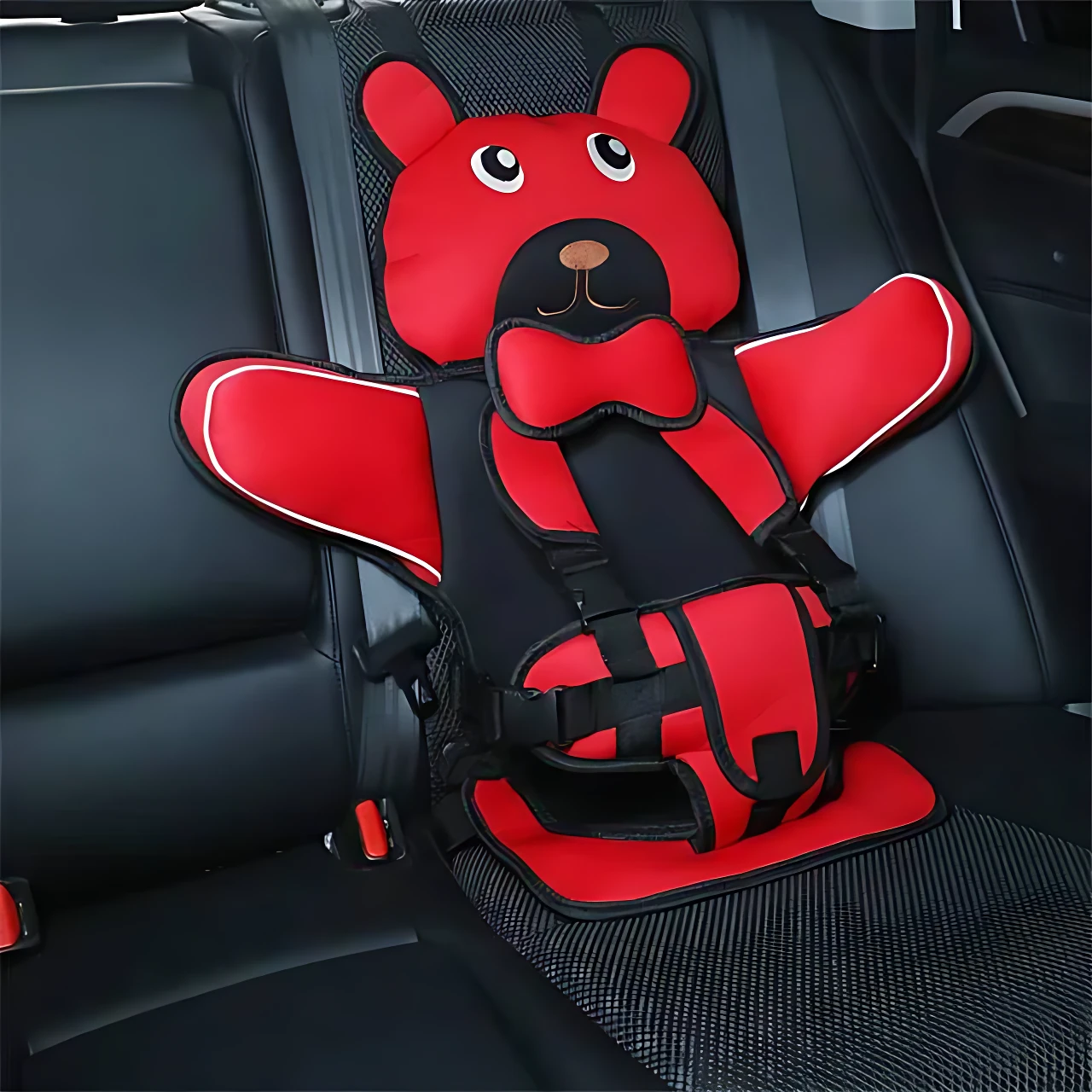 Asiento seguridad portátil para niños en color rojo con diseño de oso, instalado en asiento trasero de vehículo, con arneses y soporte lateral visible.