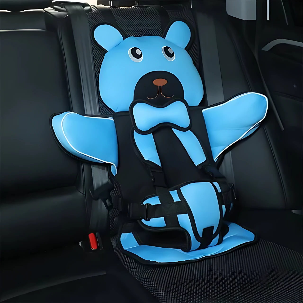 Asiento seguridad portátil para niños en color azul con diseño de oso, instalado en asiento trasero de vehículo mediante cinturón de seguridad.