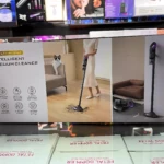 Aspiradora inteligente 2 en 1, caja blanca con de mujer usándola en sala y gato observando, detalles de accesorios y diseño compacto.