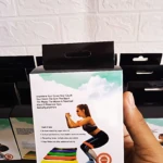 Pack de cinco bandas de resistencia con colores progresivos para entrenamiento en casa, mostradas sobre caja con modelo femenina haciendo sentadilla.