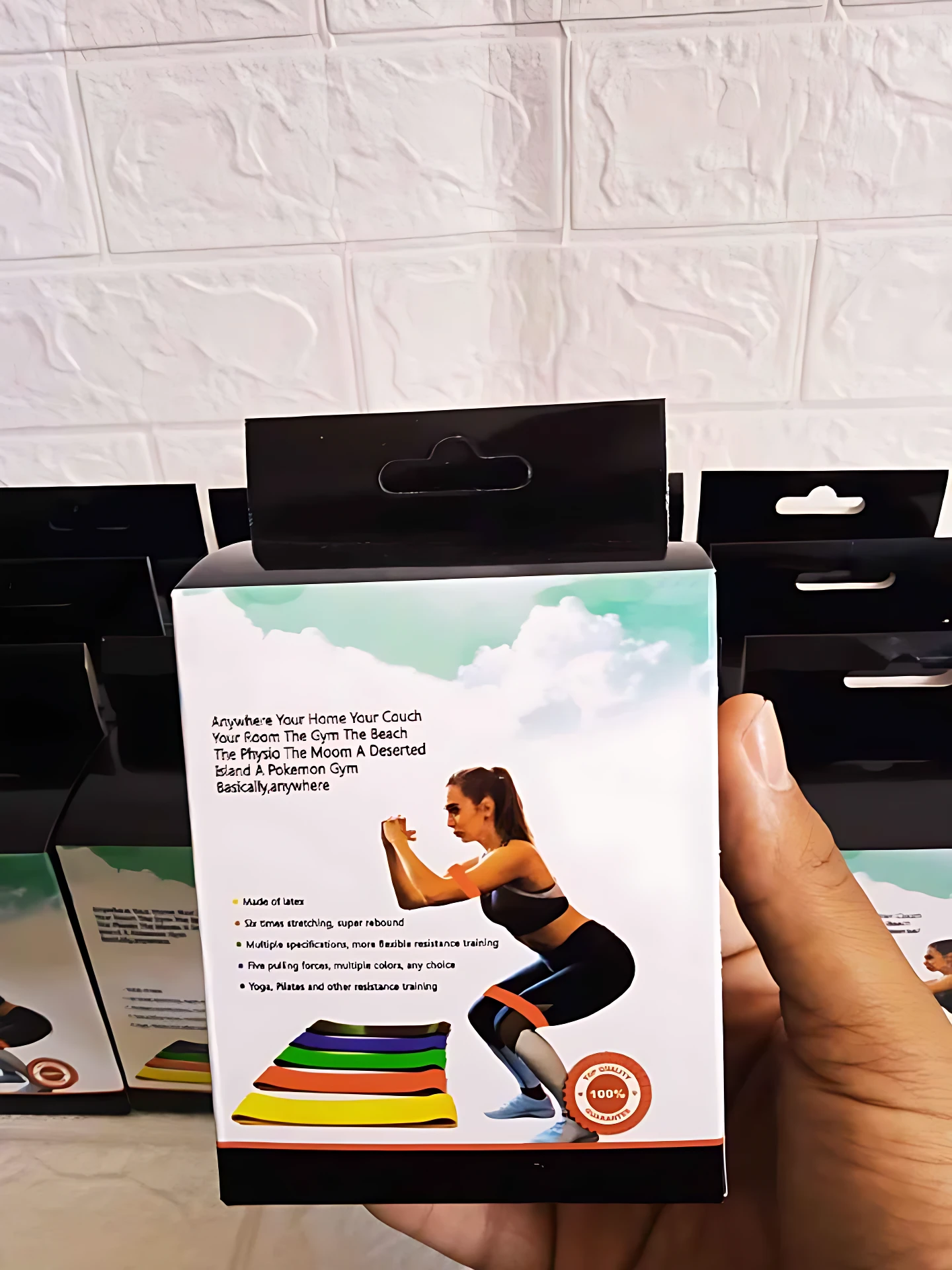 Pack de cinco bandas de resistencia con colores progresivos para entrenamiento en casa, mostradas sobre caja con modelo femenina haciendo sentadilla.