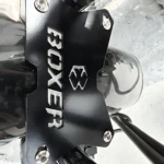 Placa de soporte negra con tornillos, marca Boxer y logotipo visible, instalada en estructura metálica de motocicleta.