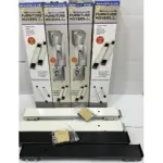 Cuatro cajas de protectores para lavadoras y neveras, con soportes metálicos y bases blancas y negras, dispuestas en fila sobre fondo blanco.