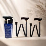 Bastón plegable de aluminio negro con mango ergonómico, desplegado y en su estuche azul; incluye tres secciones ajustables y base antideslizante.