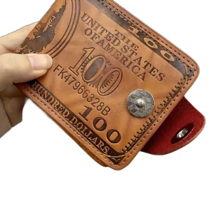 Billetera de cuero marrón con diseño de billete de cien dólares, mostrando parte del interior rojo y botón metálico.