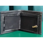 Billetera de cuero negro abierta, mostrando interior con ranuras para tarjetas y mecanismo dorado de llave en lateral derecho.