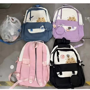 Cuatro mochilas juveniles con estampado de girasoles en colores azul, lila, rosa y negro, dispuestas sobre suelo de baldosas con una bolsa de plástico al lado.