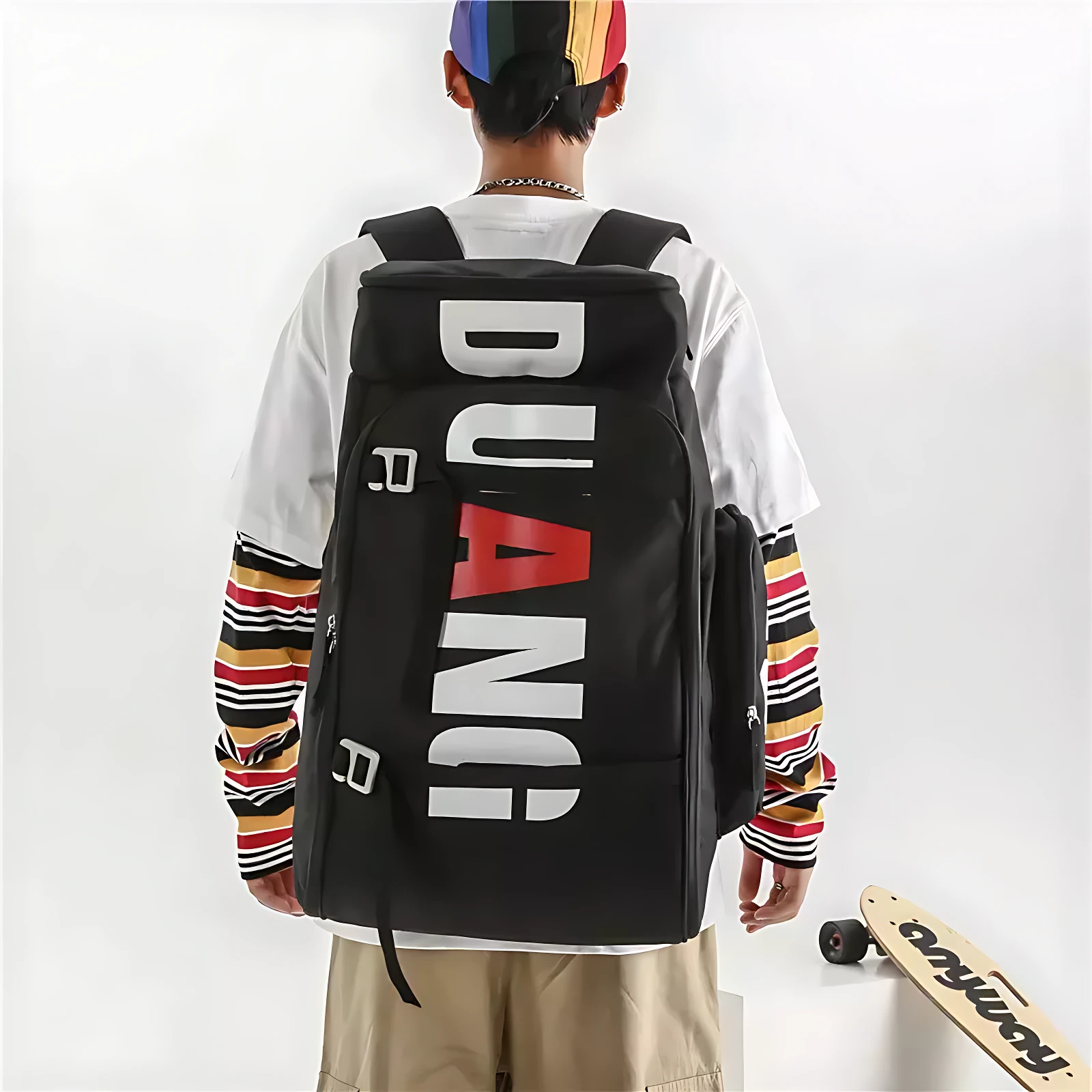 Mochila negra con letras blancas y rojas en la espalda, usada por persona con gorra multicolor y camiseta de manga larga a rayas.