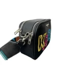 Bolso crossbody negro de Karl Lagerfeld con correa ajustable, detalles en letras multicolores y cremallera metálica.