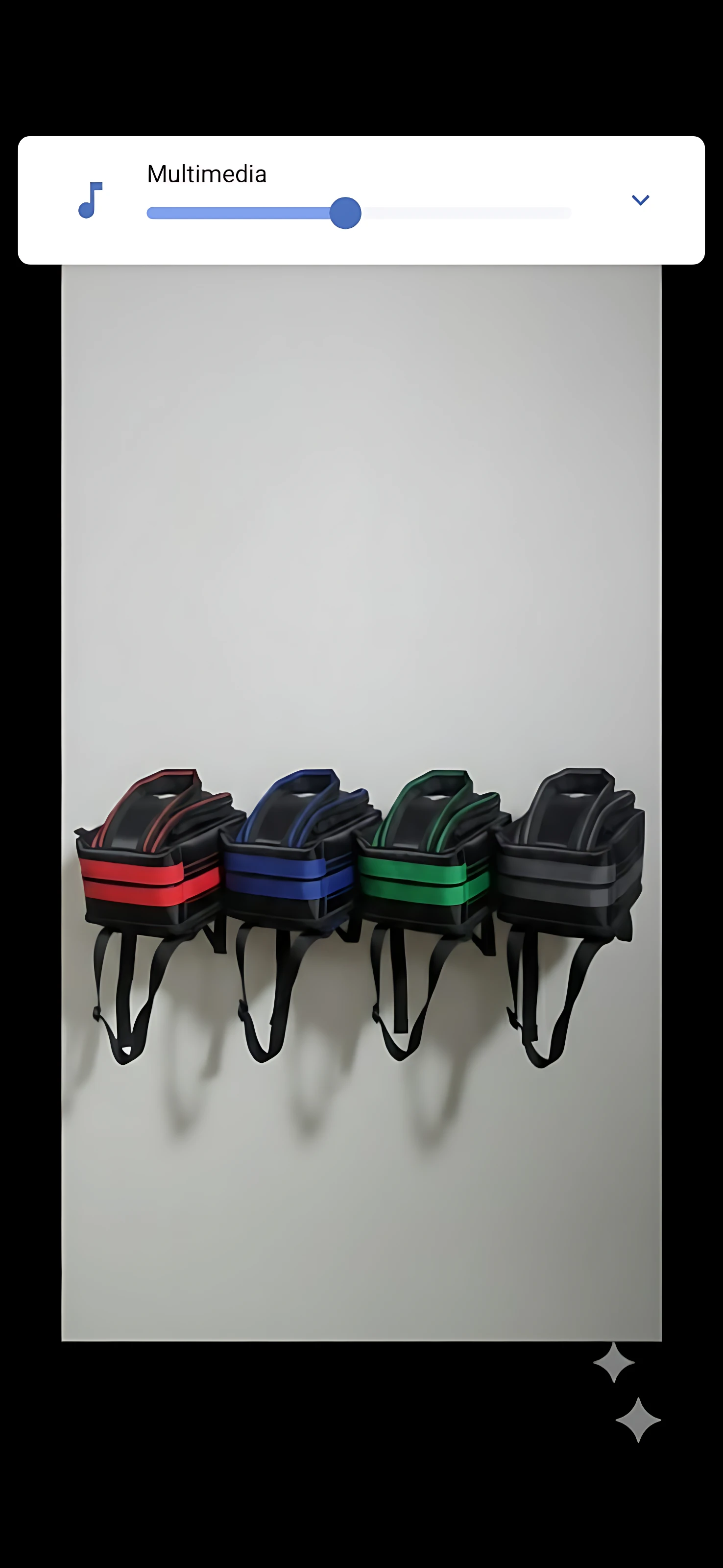 Cuatro bolsos motorizados de instalación rápida en manillar, en colores rojo, azul, verde y negro, colgados sobre pared gris.