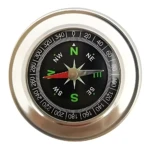 Brújula de bolsillo magnética con caja metálica plateada, dial negro con graduaciones de 0 a 360 grados y flecha roja indicando norte.