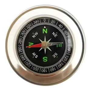 Brújula de bolsillo magnética con caja metálica plateada, dial negro con graduaciones de 0 a 360 grados y flecha roja indicando norte.