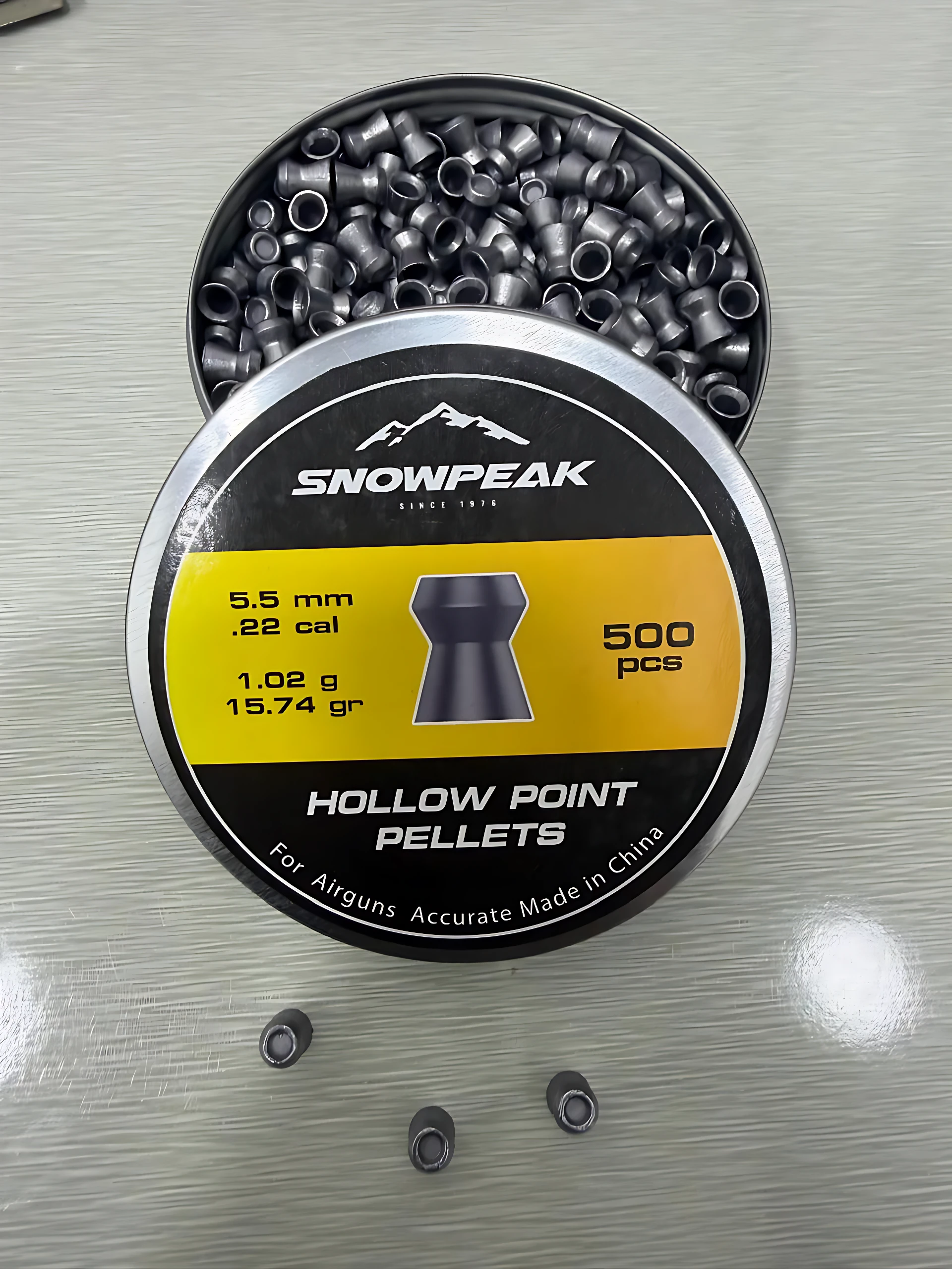 Caja redonda de diabolos Snowpeak de 5.5 mm, punta hueca, color negro, con etiqueta amarilla y texto blanco. Se ven 500 unidades dentro y tres sueltas afuera sobre superficie gris.
