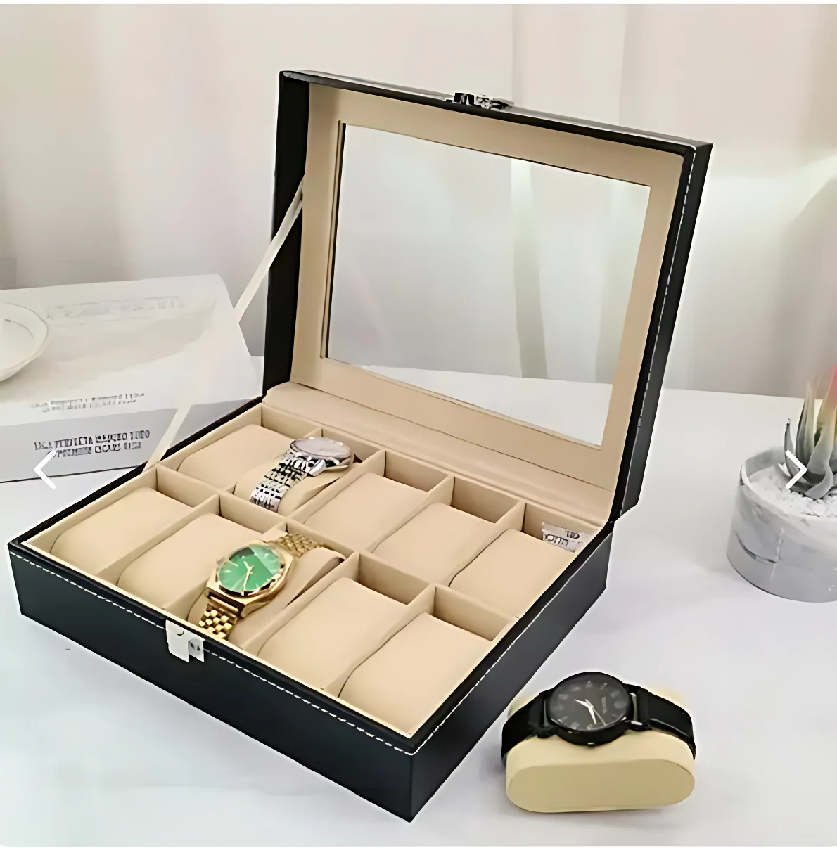 Caja organizadora de relojes con cristal superior, color negro y forro beige. Incluye espejo en tapa y compartimentos acolchados para exhibición.