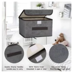 Caja organizadora de tela gris con tapa y cierre de velcro, ideal para guardar ropa en armarios; incluye detalles de textura, asas reforzadas y material transpirable.