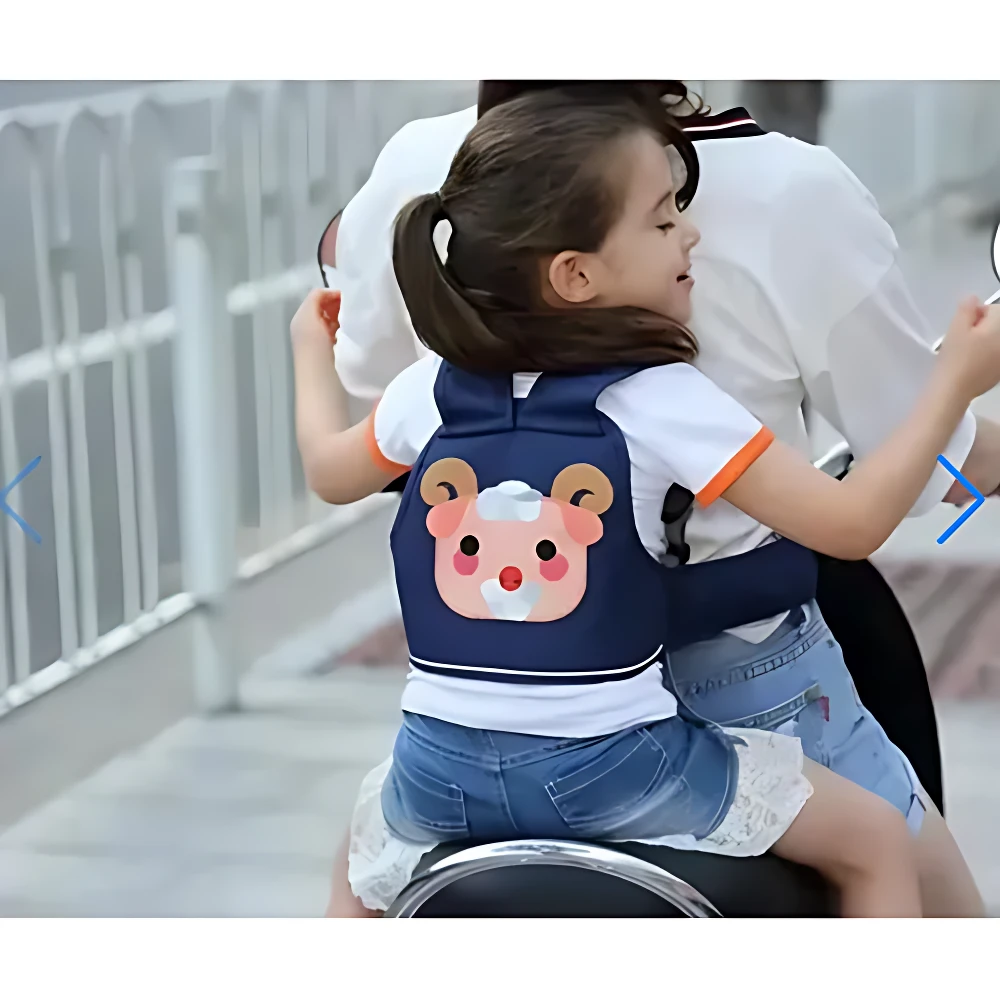 Arnés de seguridad para niños en azul marino con diseño de oso, usado por niña montada en moto eléctrica, con cinturón ajustable y respaldo acolchado.