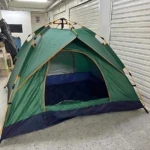 Carpa verde automática para 6 personas, montada en interior con entrada amplia y base azul oscuro.