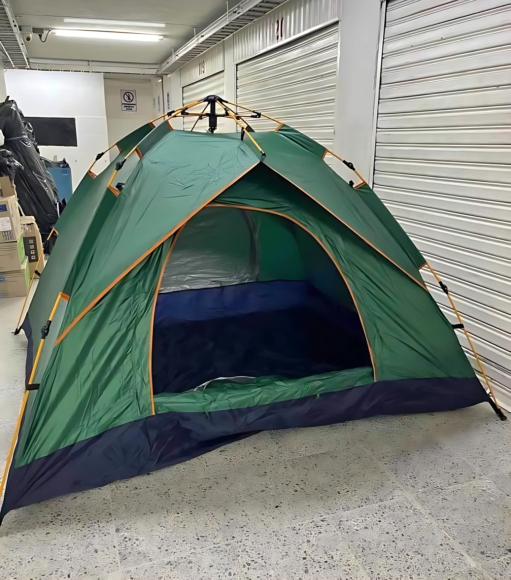 Carpa verde automática para 6 personas, montada en interior con entrada amplia y base azul oscuro.