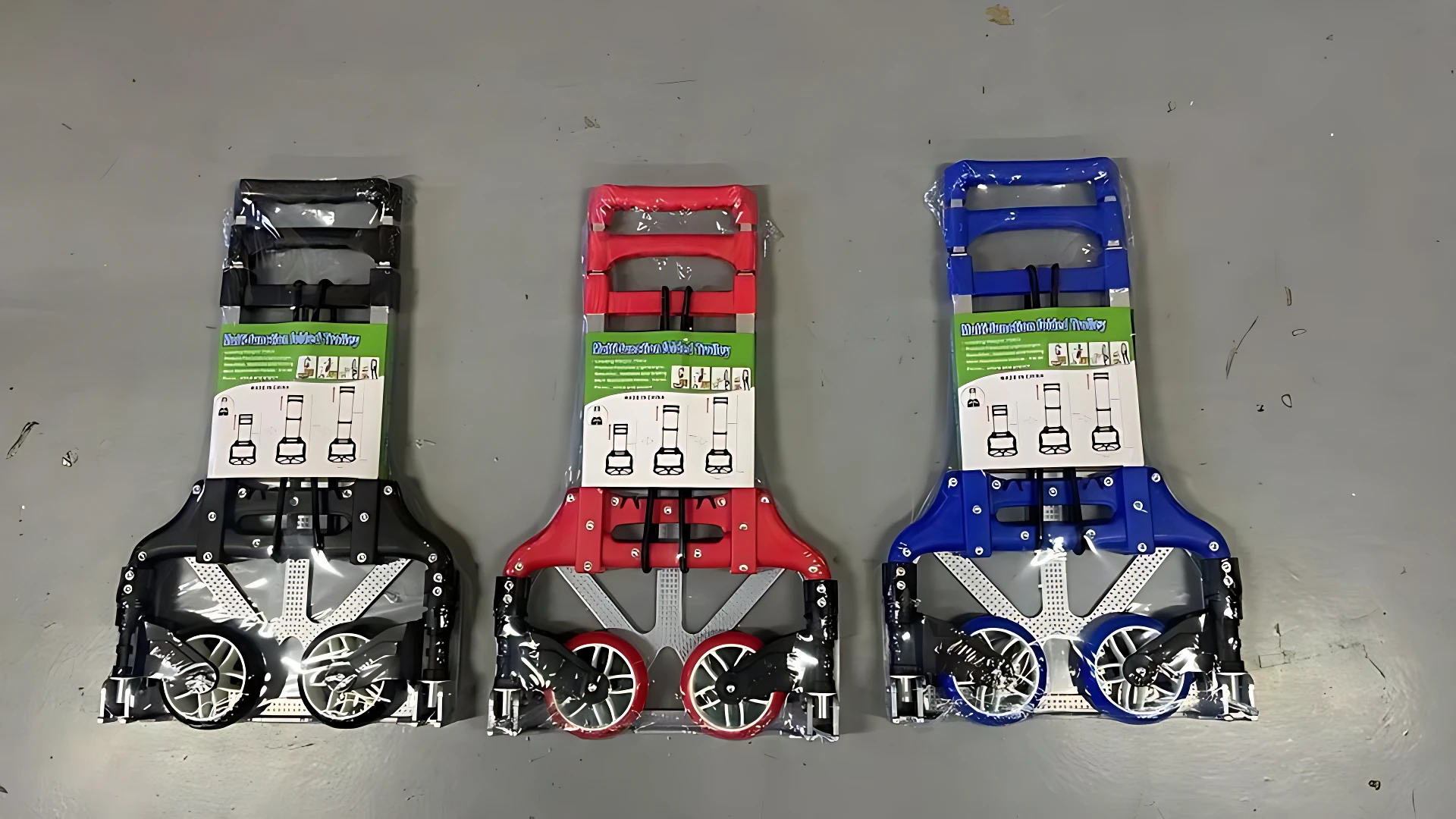 Tres carretas plegables de aluminio en negro, rojo y azul, con capacidad para 75 kg, mostradas en vista frontal sobre superficie gris.