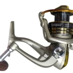 Carrete de pesca spinning Saigao, cuerpo metálico color gris con detalles dorados, mango de madera y sistema Line Roller visible en la parte superior.