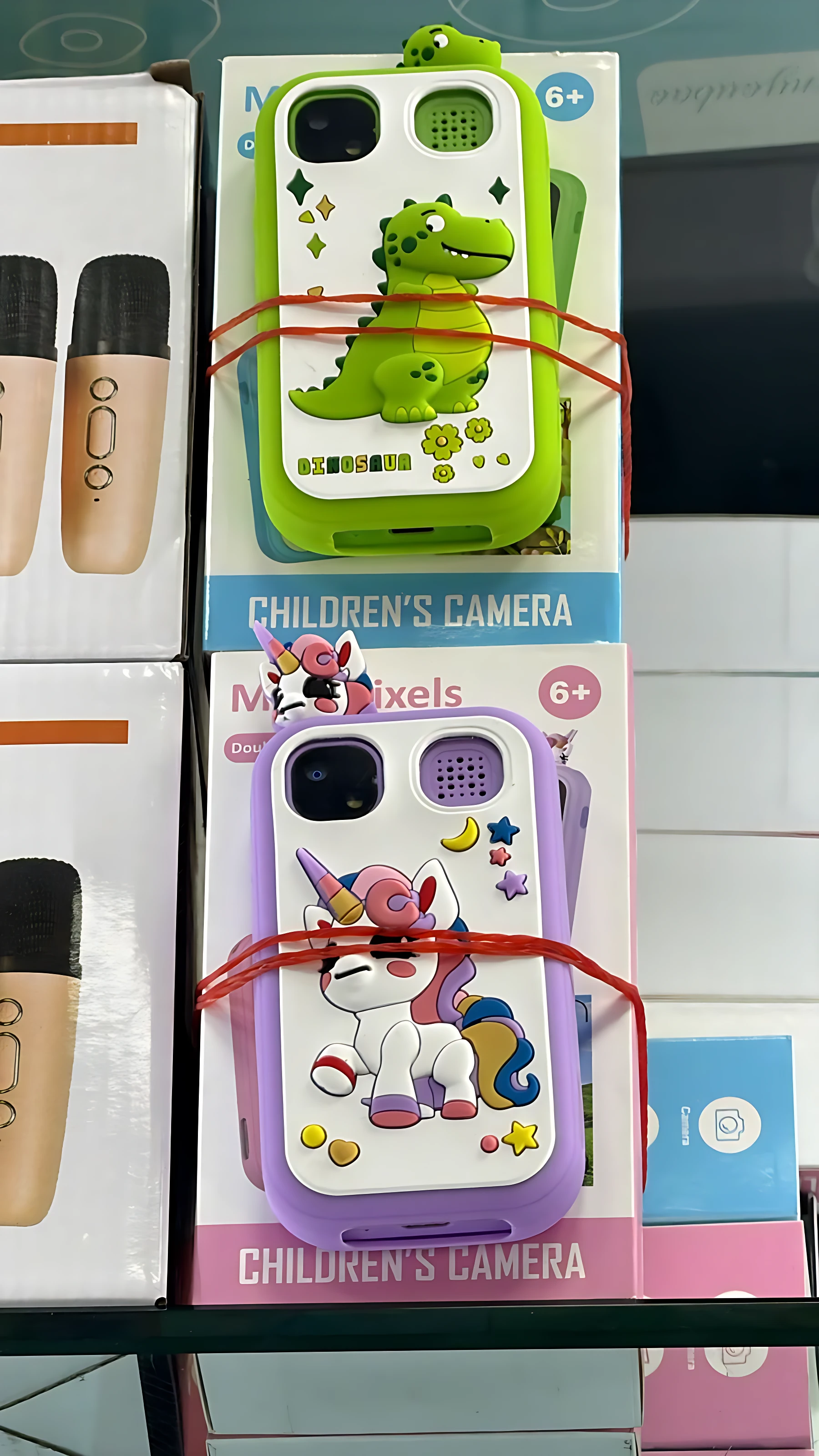 Caja de teléfono infantil con cámara doble, diseño de dinosaurio verde y unicornio morado, con protección de bordes y accesorios incluidos.