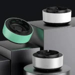 Tres ceniceros purificadores de aire en colores verde menta, blanco y gris plateado, con diseño cilíndrico y ventilación superior visible, sobre pedestales oscuros.