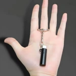 Encendedor eléctrico tipo C por soplido, color negro, con cable USB-C y anillo de llave, sostenido en mano abierta sobre fondo gris.