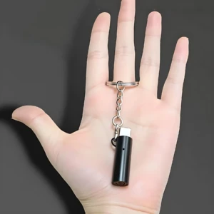 Encendedor eléctrico tipo C por soplido, color negro, con cable USB-C y anillo de llave, sostenido en mano abierta sobre fondo gris.