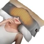 Máscara para ojos con perlas de vidrio, color gris con luz cálida, usada sobre almohada en reposo.
