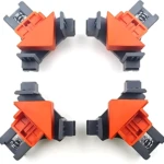 Cuatro clips de fijación angular en naranja y gris, dispuestos en cuadrícula, para ensamblaje preciso de muebles y marcos.