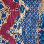 Cobija térmica para cama doble con diseño floral en tonos azul, rojo y dorado, textura suave y bordes decorativos.