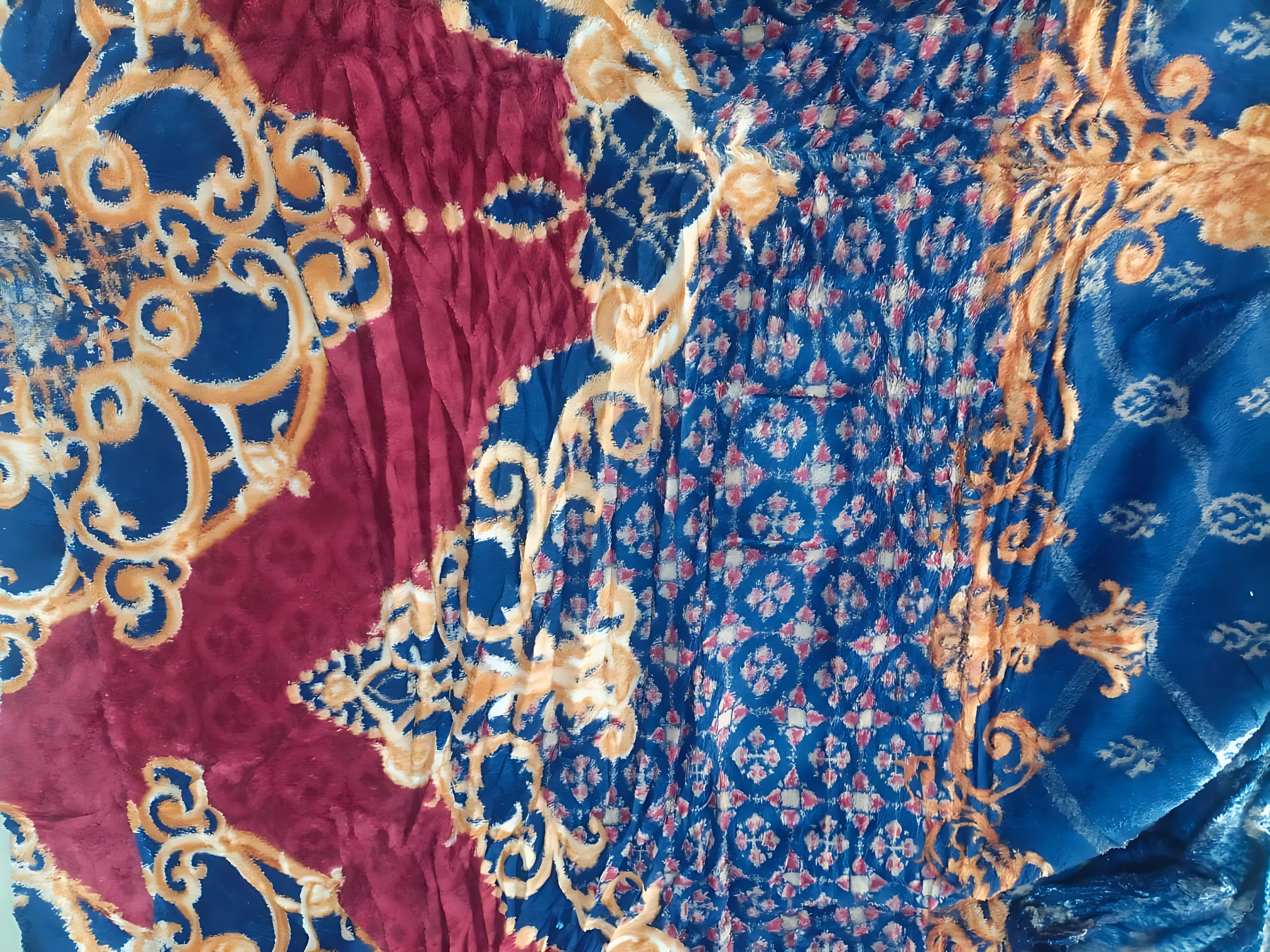 Cobija térmica para cama doble con diseño floral en tonos azul, rojo y dorado, textura suave y bordes decorativos.