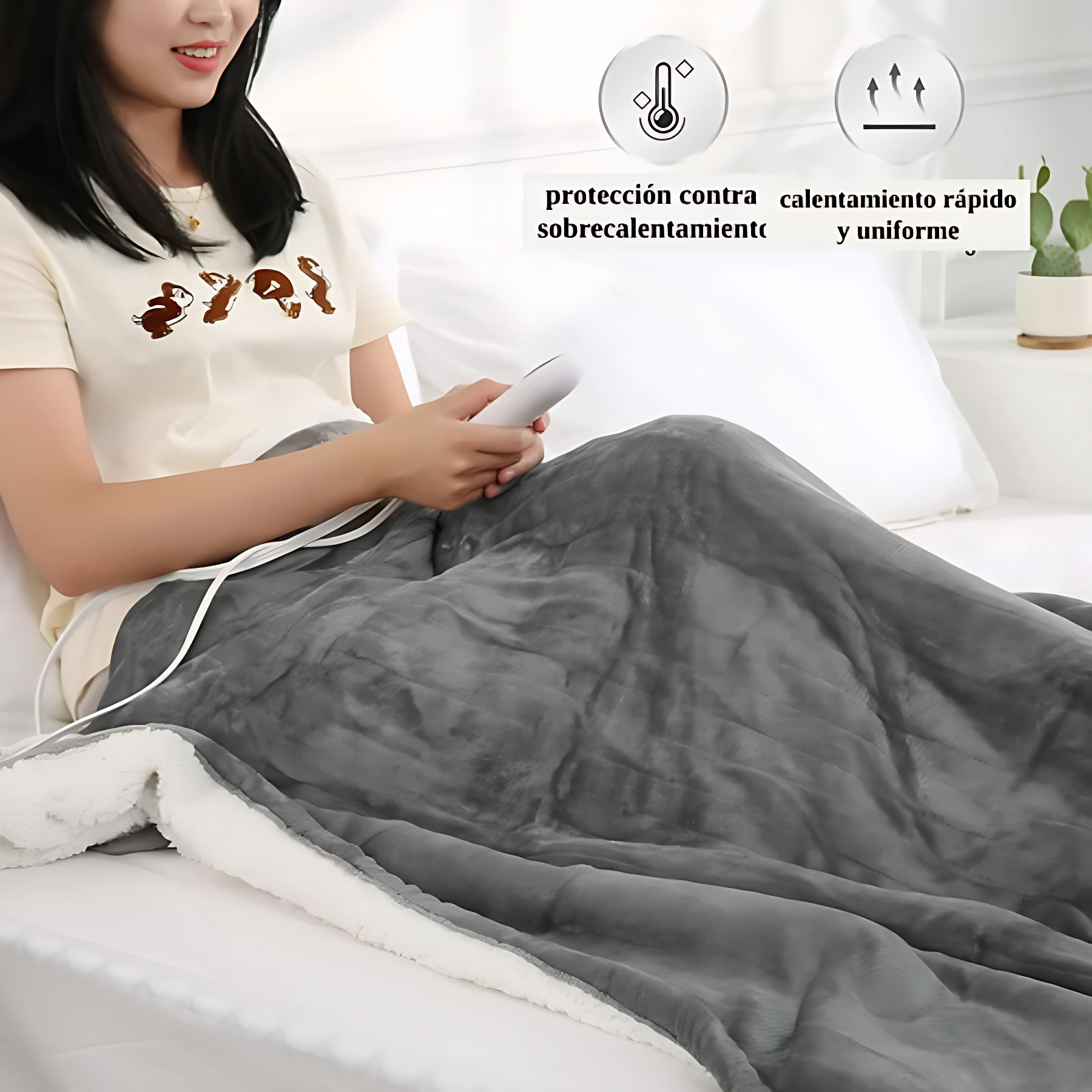 Cobija eléctrica gris con interior blanco, usada por mujer en cama; incluye control remoto y muestra protección contra sobrecalentamiento.
