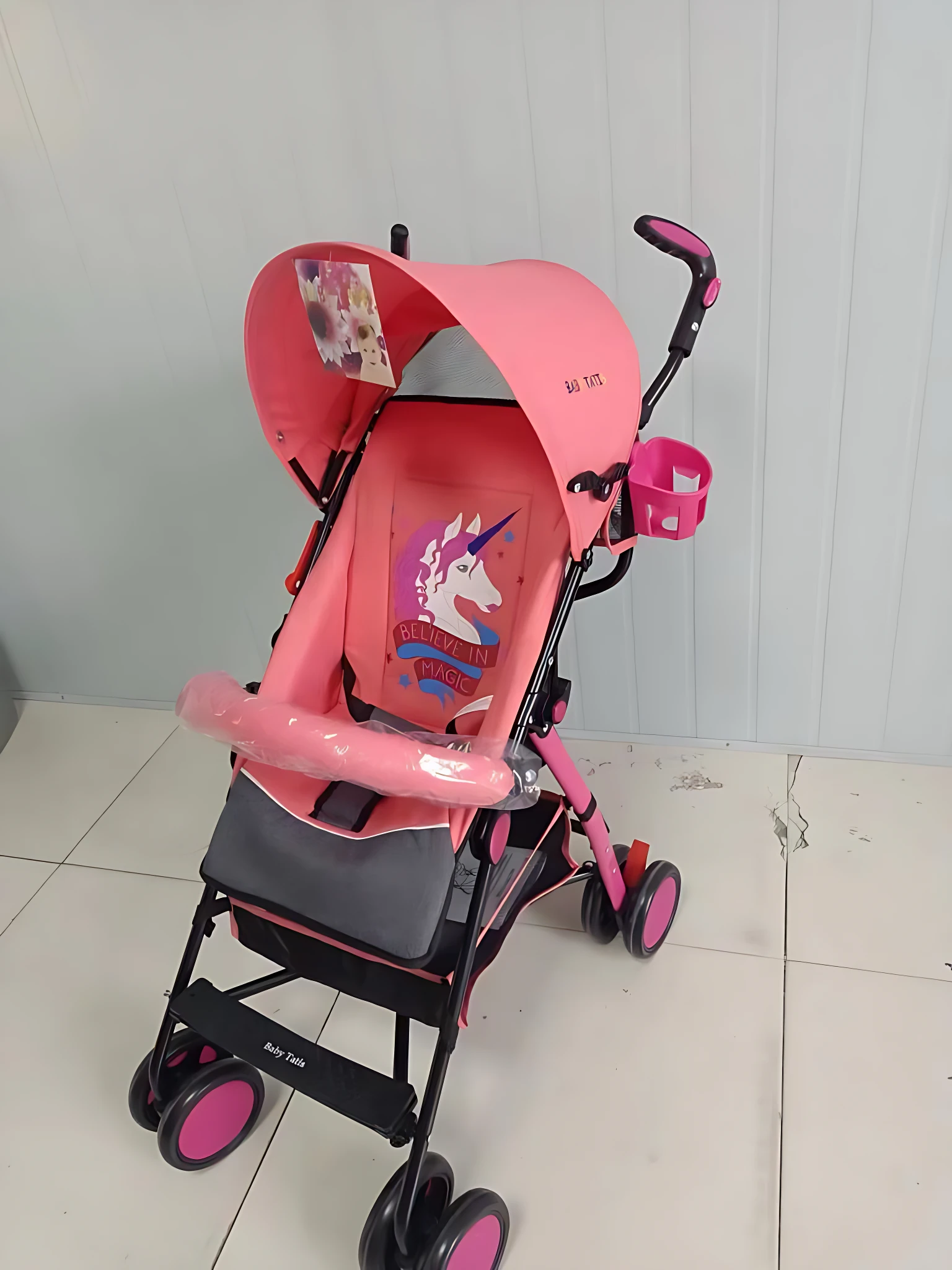 Coche paseador tipo sombrilla en color rosa con capota, asientos acolchados y ruedas giratorias. Incluye reposabrazos y cazoleta lateral. Ideal para uso diario y transporte ligero.