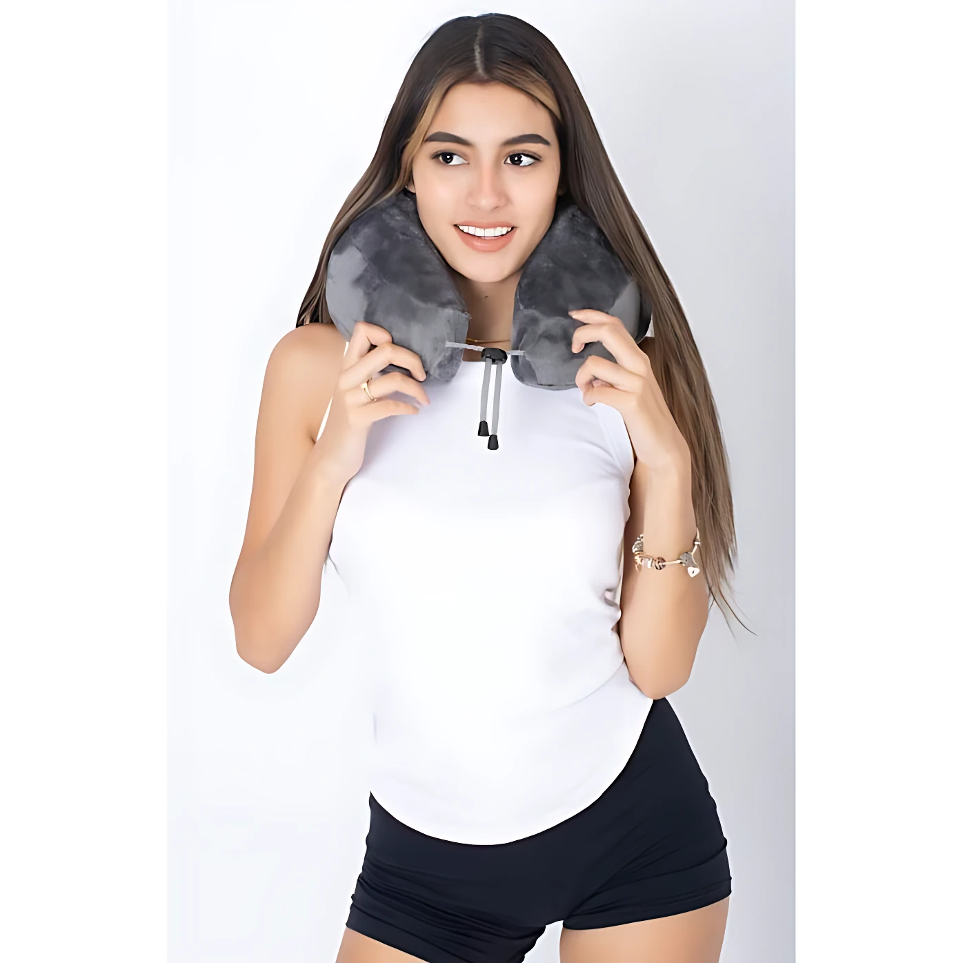 Mujer joven usando cojín cervical gris con espuma viscoelástica, ajustable por cordón, en pose frontal sobre fondo blanco.