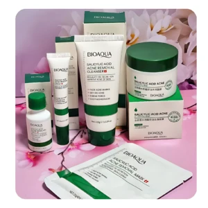 Set de cinco productos Bioaqua con ácido salicílico, envases blancos y tapas verdes sobre fondo rosa con flores. Incluye limpiador, tónico, crema, suero y mascarilla facial.