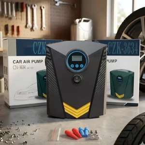 Compresor portátil negro con detalles amarillos y pantalla digital, acompañado de accesorios y caja de presentación en entorno de taller.