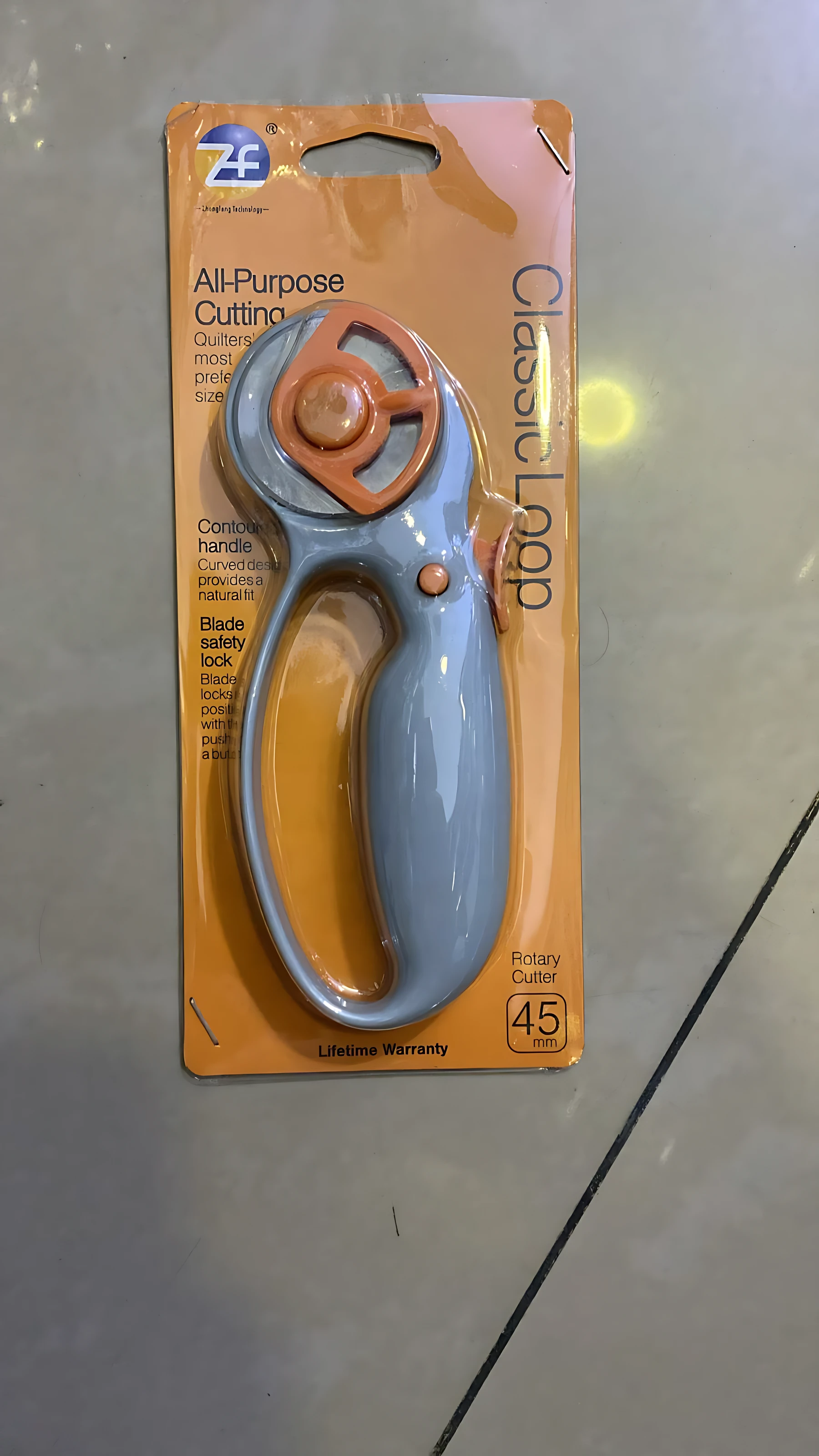Cortador giratorio ZF Classic Loop en su empaque naranja, con mango azul claro y rueda naranja, diseñado para manualidades.