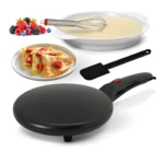 Crepera eléctrica negra con mango rojo, junto a sartén blanca con mezcla, espátula y crepes servidos con frutas.