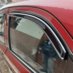Deflector de ventana para auto rojo, con goma flexible y marco cromado, instalado en puerta lateral, bloquea lluvia y viento sin cerrar cristal.