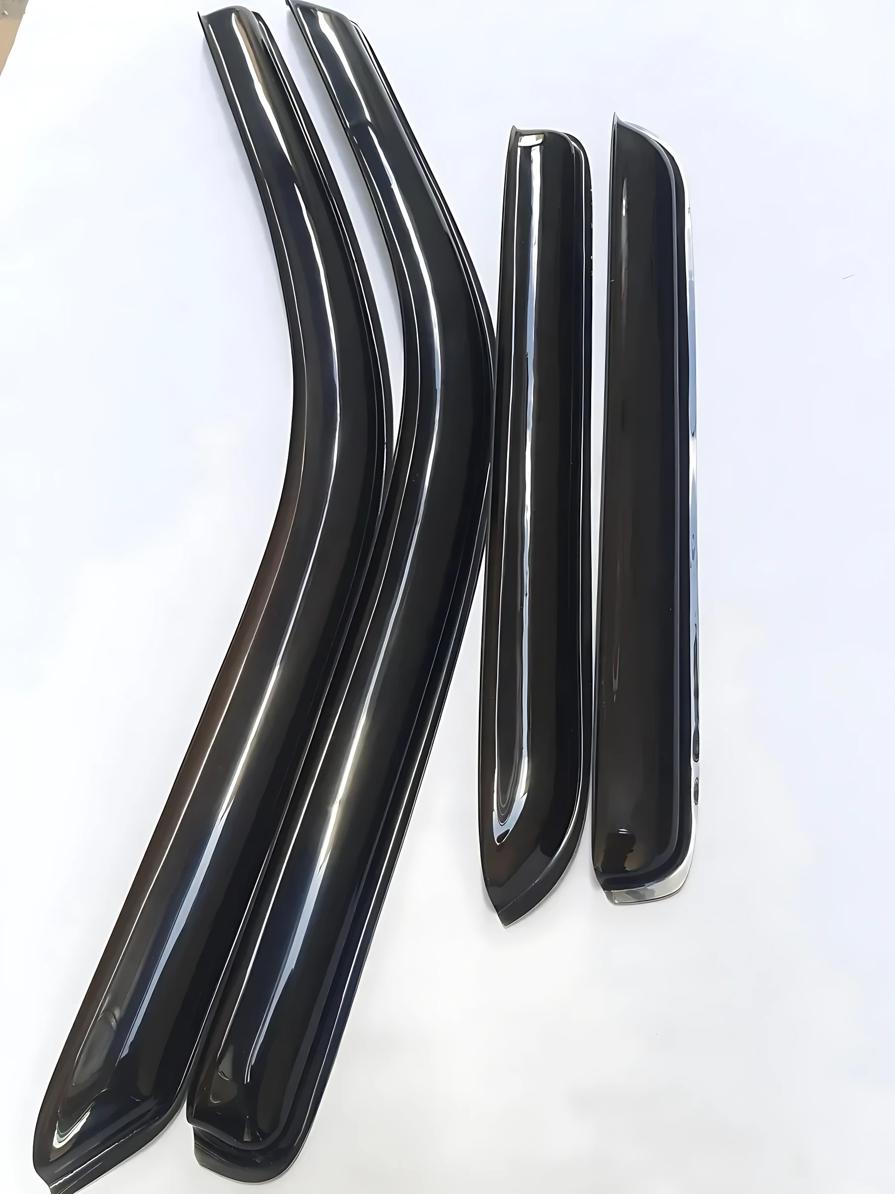 Cuatro deflectores de ventana negros con goma flexible, dispuestos en dos pares curvos y rectos sobre fondo blanco.