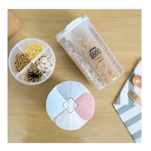 Dispensador hermético de 4 espacios con granos y palillos, sobre mesa de madera.