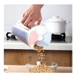 Dispensador de granos hermético con tapa de cuatro compartimentos en colores pastel, siendo usado para verter sojas en un bowl de vidrio sobre encimera de madera.